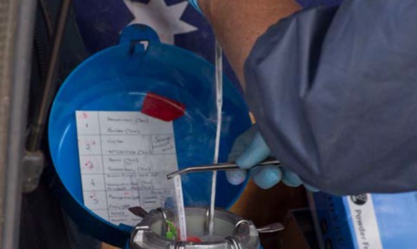 A farmer breeding cows using semen flask equipment.
